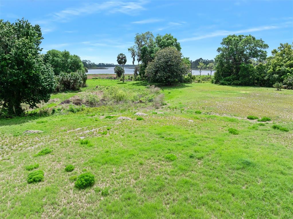 A grassy, open lot features scattered trees and a view of a distant body of water — 141 N PINE STREET, PIERSON, FL