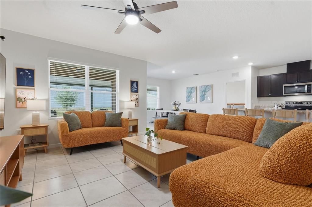 A living room with orange textured sofas, a wooden coffee table, and an open kitchen — 1113 GRIFFON AVE, LAKE ALFRED, FL