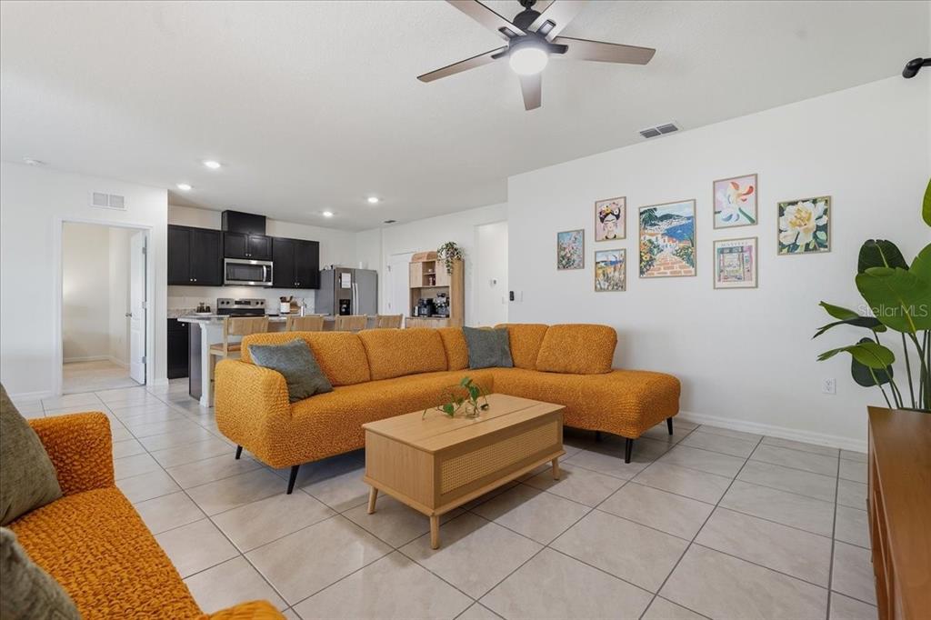 A living room with an orange sectional sofa, a coffee table, and an open kitchen — 1113 GRIFFON AVE, LAKE ALFRED, FL