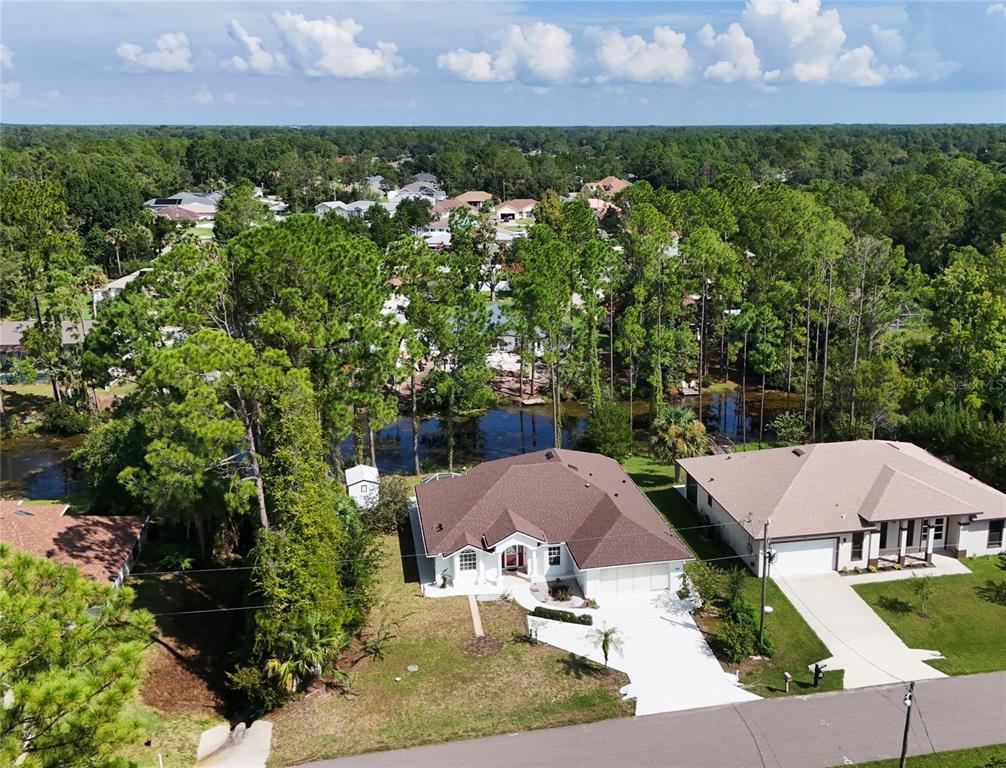 An aerial view shows a suburban house with a brown roof near a small lake — 64 WHITTINGTON DRIVE, PALM COAST, FL