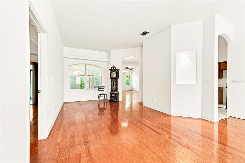An empty room with hardwood floors, a grandfather clock, and an arched doorway — 64 WHITTINGTON DRIVE, PALM COAST, FL