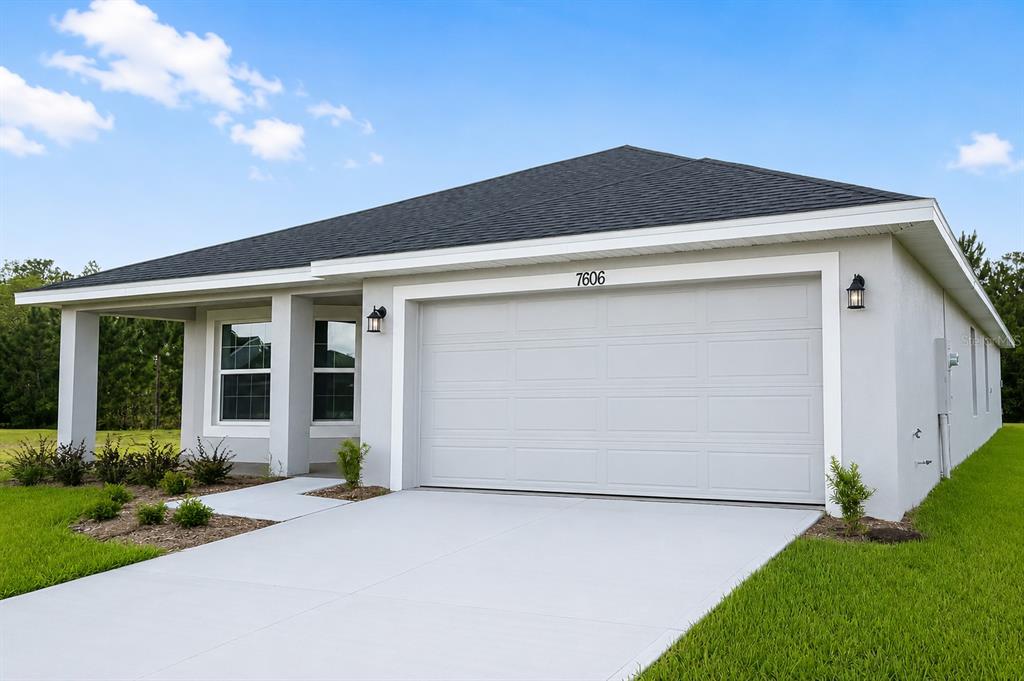 A single-story house with a gray stucco exterior, a two-car garage, and a covered porch — 7606 BENT TREE LOOP, ST CLOUD, FL