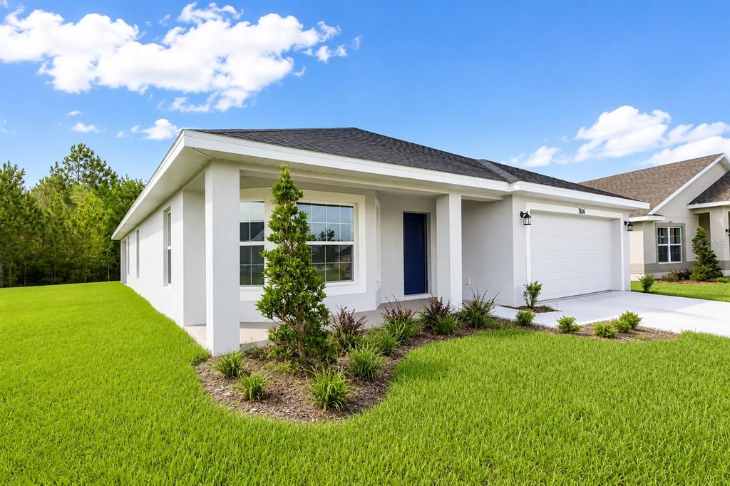 A single-story house with a white stucco exterior, a blue front door, and a garage — 7606 BENT TREE LOOP, ST CLOUD, FL