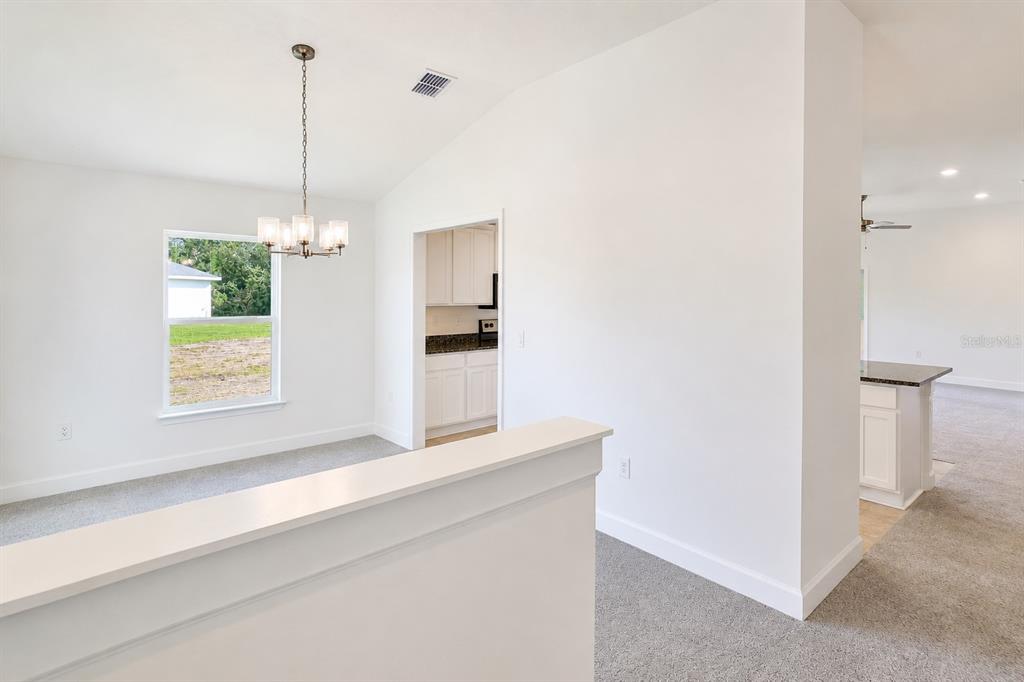 A dining area with a chandelier and a view into a white kitchen — 7606 BENT TREE LOOP, ST CLOUD, FL