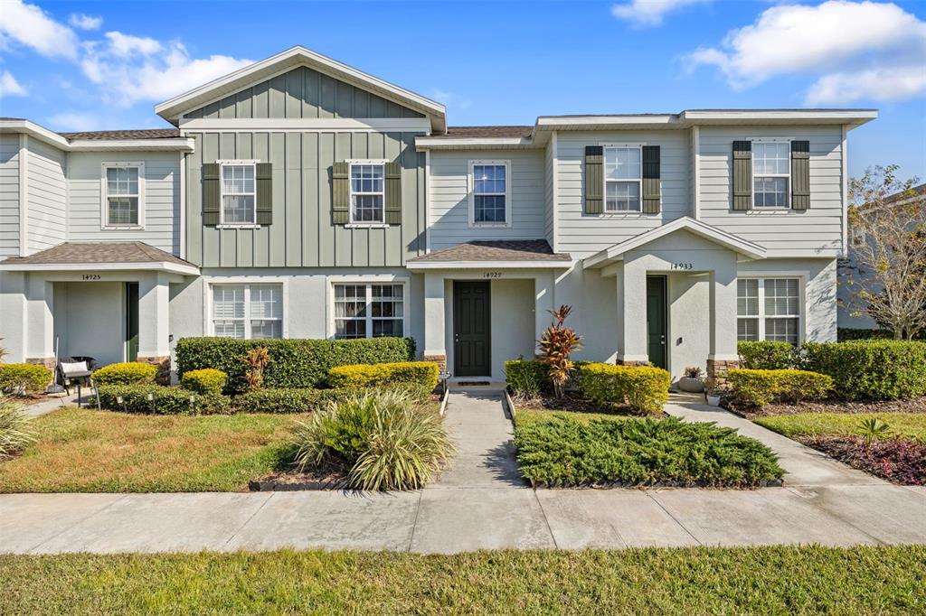 A multi-unit residential building with light-colored siding, dark shutters, and small front porches — 14929 PROMENADE PARKWAY, ODESSA, FL