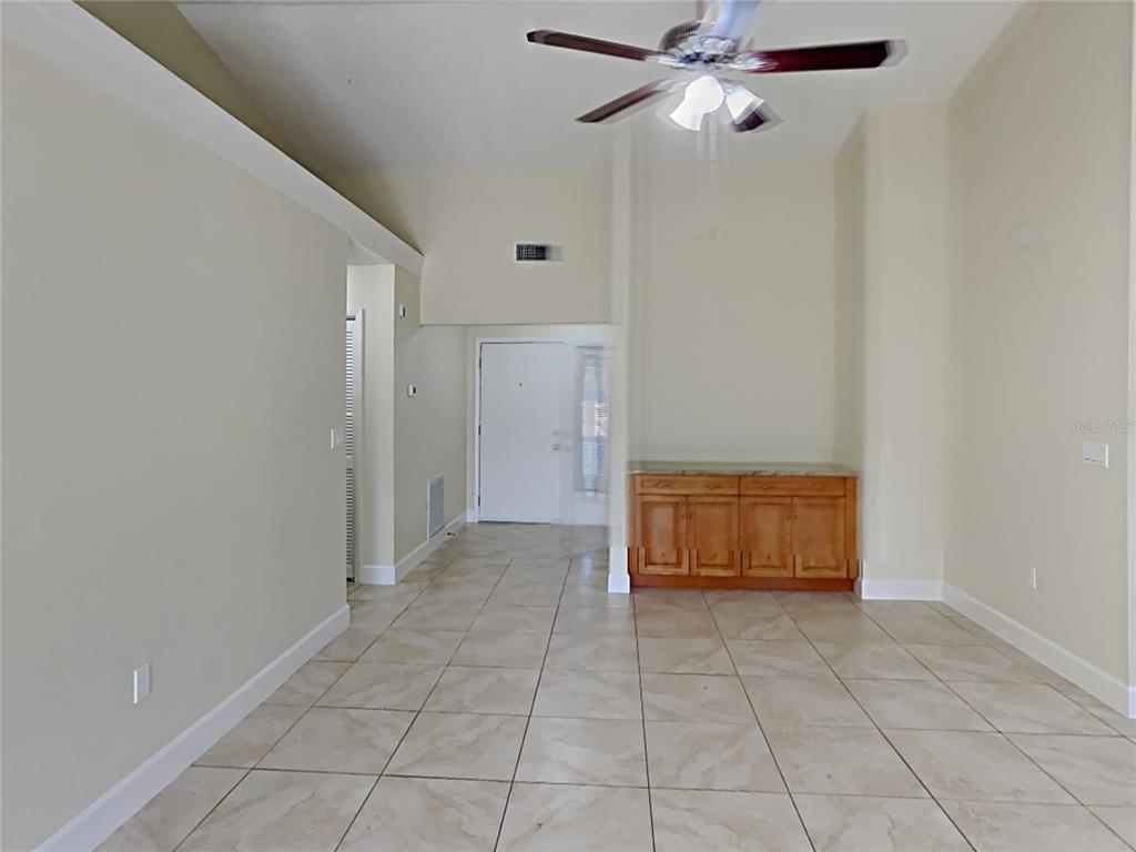 An open living area features light tile flooring, a ceiling fan, and a wooden cabinet — 1320 NOELL BOULEVARD, PALM HARBOR, FL