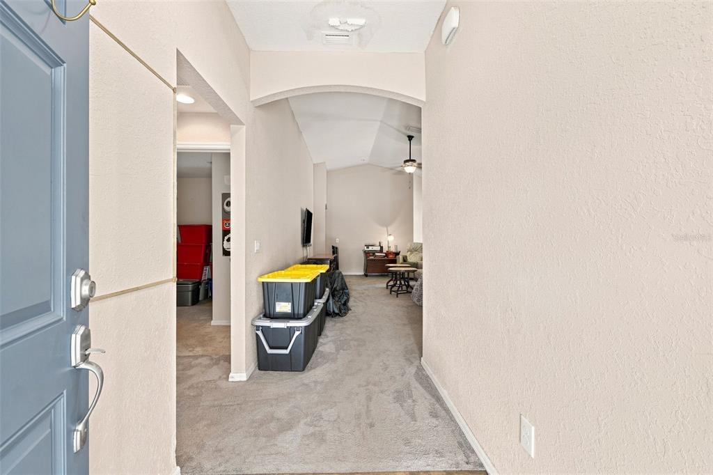 An entryway with gray carpet leads into a living area featuring an arched doorway — 322 WOODS LANDING DRIVE, LADY LAKE, FL