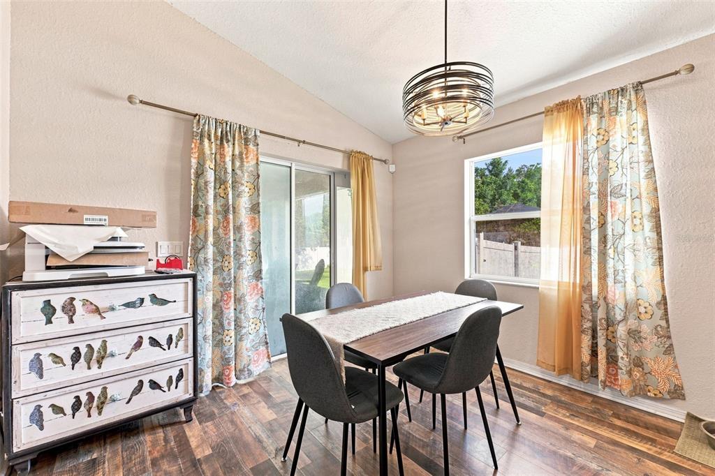 A dining room features a wooden table, four chairs, a bird-patterned dresser, and floral curtains — 322 WOODS LANDING DRIVE, LADY LAKE, FL