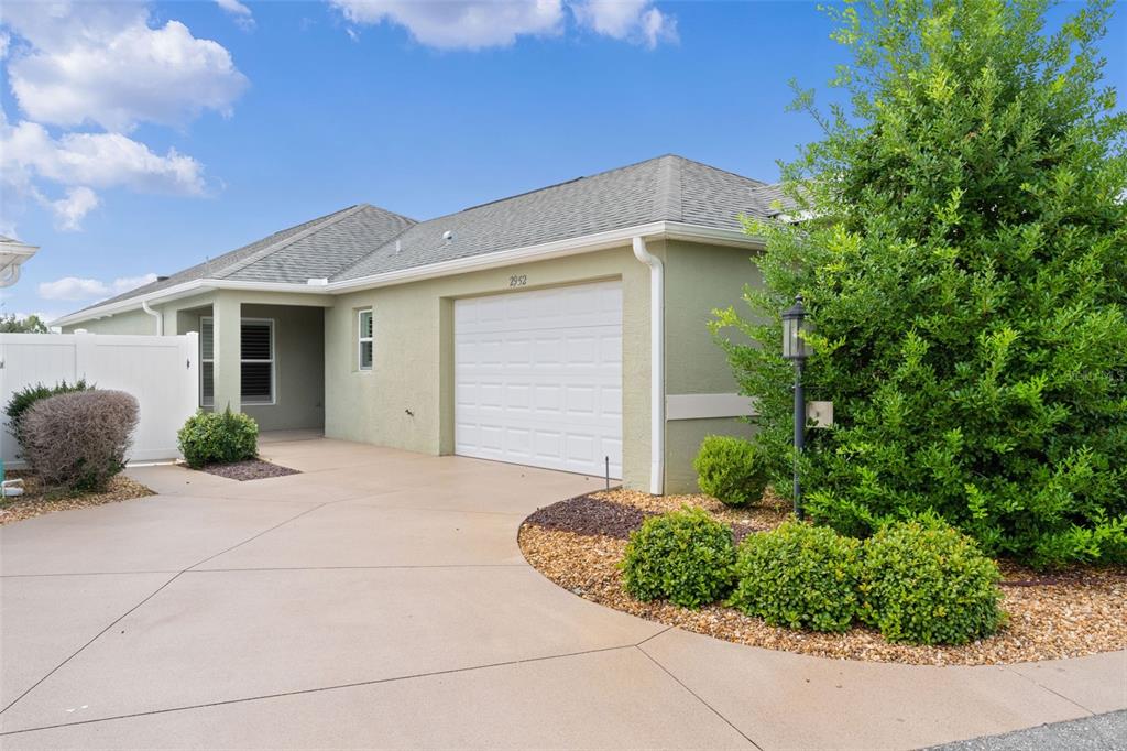 A single-story house with a light green exterior, a white garage door, and a concrete driveway — 2952 KRAMER COURT, THE VILLAGES, FL