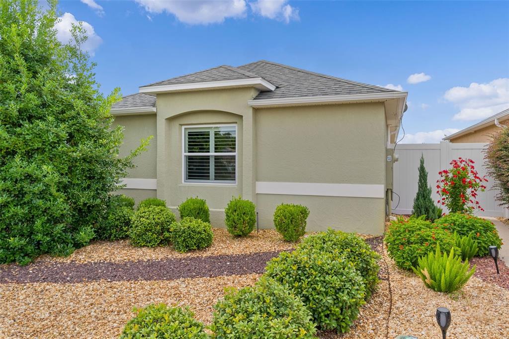 The exterior of a single-story house features light-colored stucco walls, a shingled roof, and landscaping — 2952 KRAMER COURT, THE VILLAGES, FL