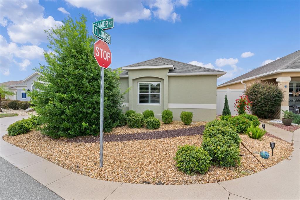 A single-story house exterior features a gravel yard, a stop sign, and street name signs — 2952 KRAMER COURT, THE VILLAGES, FL