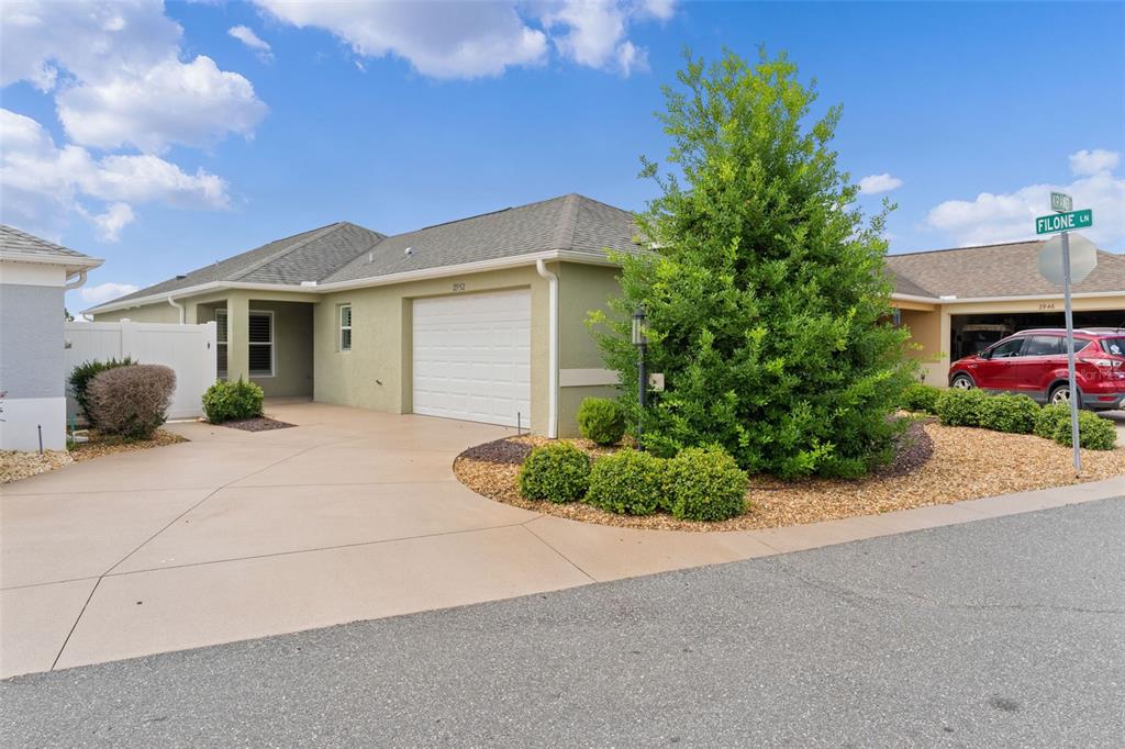 A single-story house with a light green exterior, a two-car garage, and a large tree — 2952 KRAMER COURT, THE VILLAGES, FL