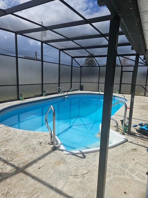 An outdoor swimming pool is enclosed by a screened-in lanai with a concrete deck — 619 N FIRWOOD DRIVE, DELTONA, FL