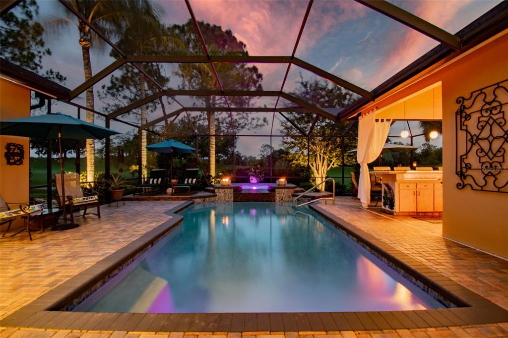 A screened-in swimming pool and spa area with a patio and outdoor kitchen at sunset — 17714 GREY EAGLE ROAD, TAMPA, FL
