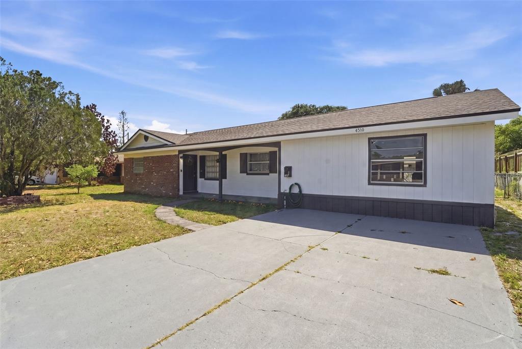 A single-story house with white vertical siding, a brick section, and a concrete driveway — 4510 FETROW DRIVE, ORLANDO, FL