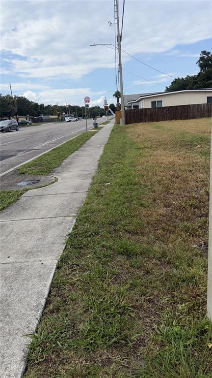 A sidewalk runs alongside a grassy lot and a road with a wooden fence nearby — 4341 LENOX BOULEVARD, ORLANDO, FL