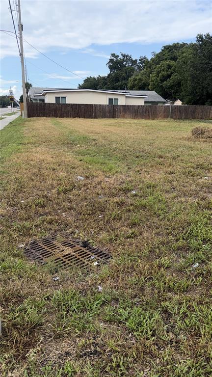 A vacant grassy lot with a storm drain grate and a wooden fence in back — 4341 LENOX BOULEVARD, ORLANDO, FL