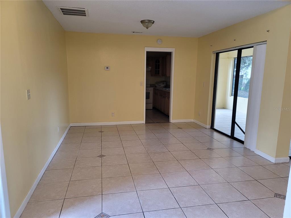 A dining area with beige tile flooring, yellow walls, and a sliding glass door — 41 CHIP COURT, KISSIMMEE, FL