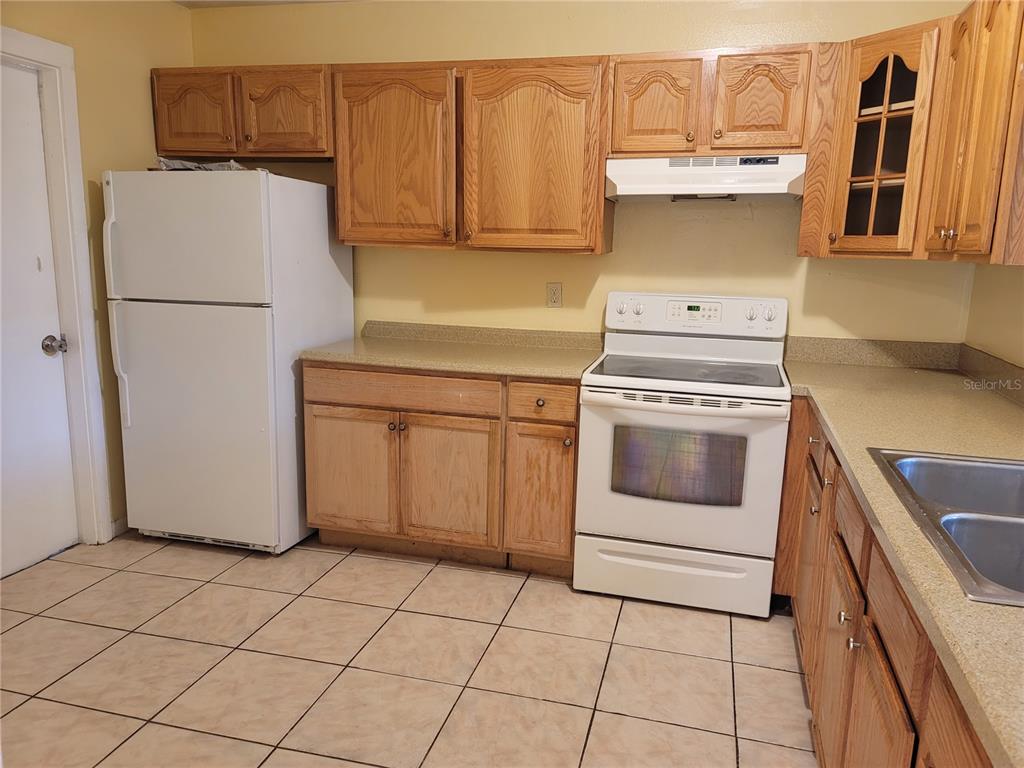A kitchen features light oak cabinets, white appliances, a tiled floor, and laminate countertops — 41 CHIP COURT, KISSIMMEE, FL
