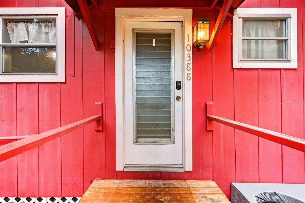 A red exterior wall features a white front door with a glass insert and railings — 10388 SW 64TH AVENUE, BUSHNELL, FL