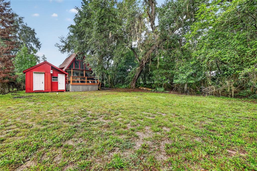 A red shed stands next to an A-frame house surrounded by trees and grass — 10388 SW 64TH AVENUE, BUSHNELL, FL