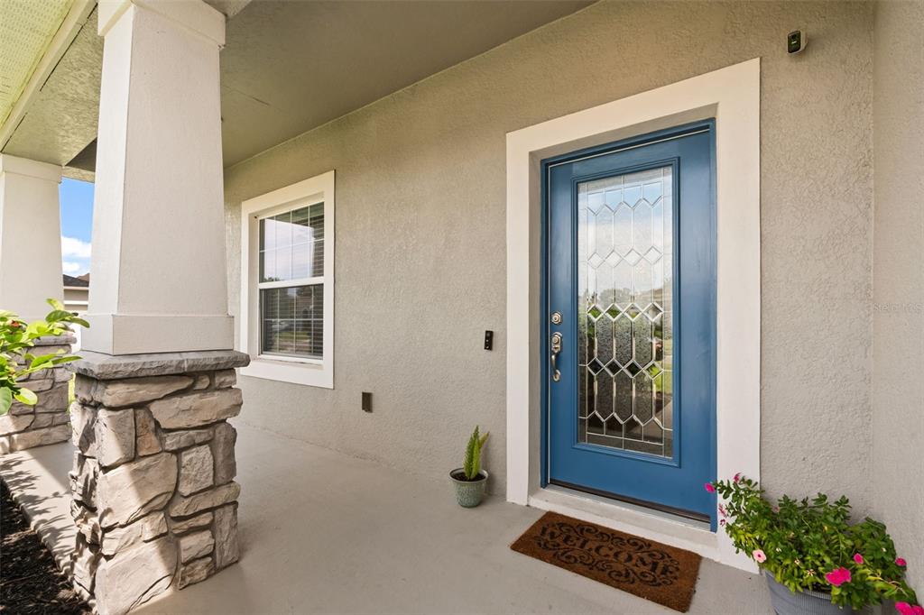 A blue front door with a glass insert sits on a covered porch with stone columns — 184 BELLA VERANO WAY, DAVENPORT, FL