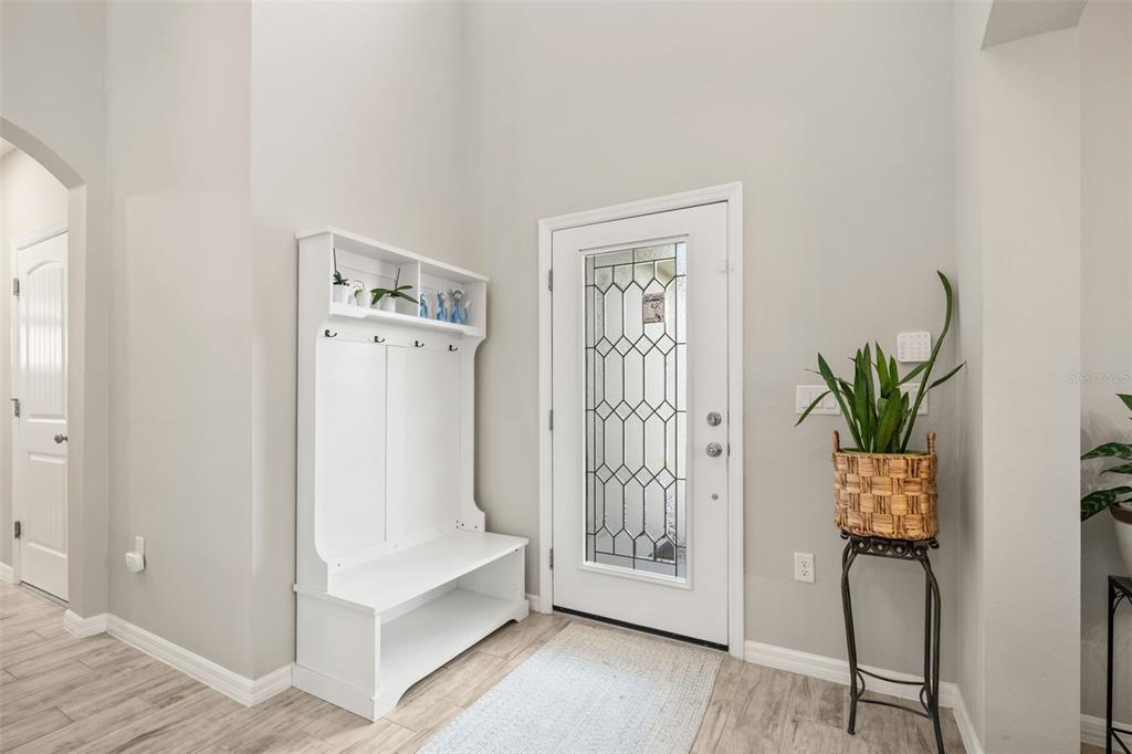 An entryway features a white hall tree, a glass-paneled front door, and a potted plant — 184 BELLA VERANO WAY, DAVENPORT, FL