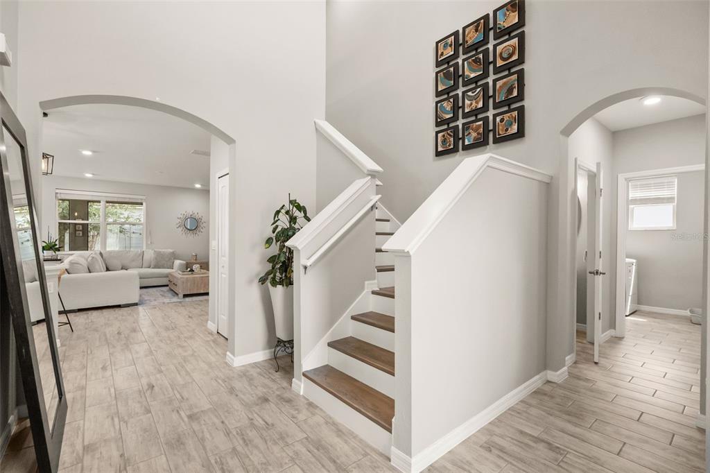 An entryway features a staircase with wood treads, light tile flooring, and a gallery wall — 184 BELLA VERANO WAY, DAVENPORT, FL