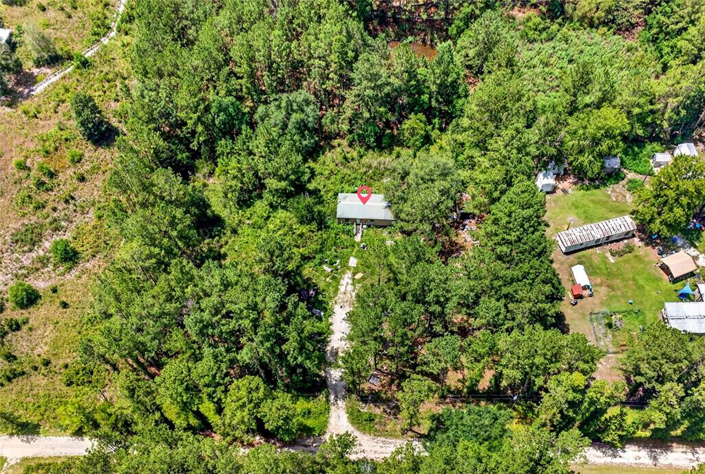 An aerial view shows a house nestled in a wooded lot with a gravel driveway — 7320 NE 137TH PLACE, CITRA, FL