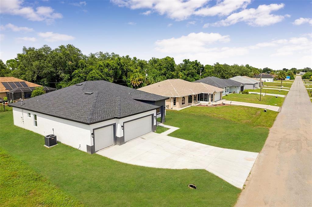 An aerial view shows a modern white house with a dark roof and a concrete driveway — 8274 MOSSBORGER AVENUE, NORTH PORT, FL