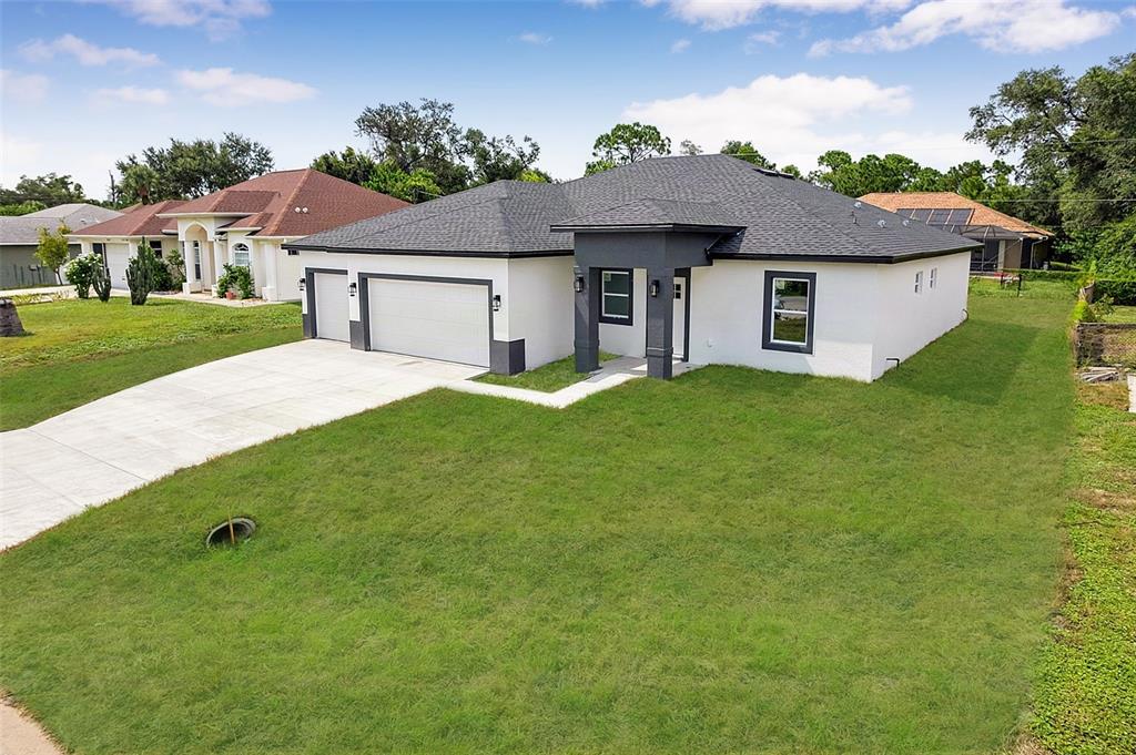 A single-story house with a white exterior, dark gray roof, and a two-car garage — 8274 MOSSBORGER AVENUE, NORTH PORT, FL