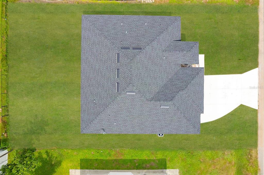 An aerial view shows the dark shingled roof of a house surrounded by a green lawn — 8274 MOSSBORGER AVENUE, NORTH PORT, FL