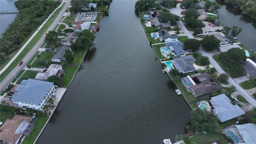 An aerial view shows a canal lined with residential houses, swimming pools, and a road — 560 7TH STREET S, SAFETY HARBOR, FL