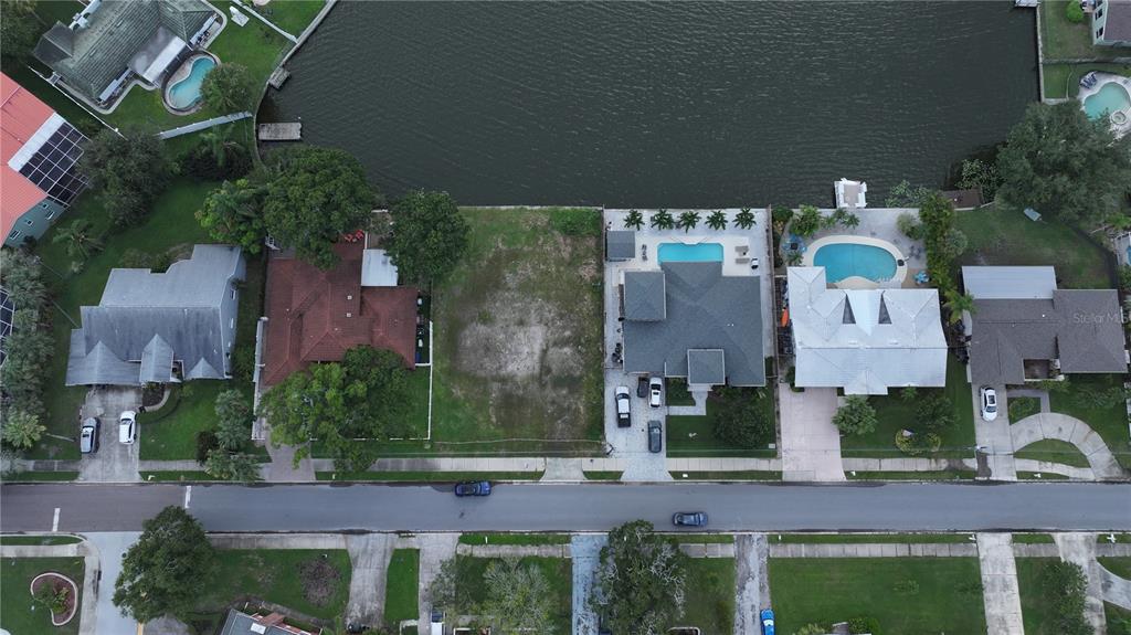 An aerial view shows a vacant waterfront lot situated between two residential homes with pools — 560 7TH STREET S, SAFETY HARBOR, FL