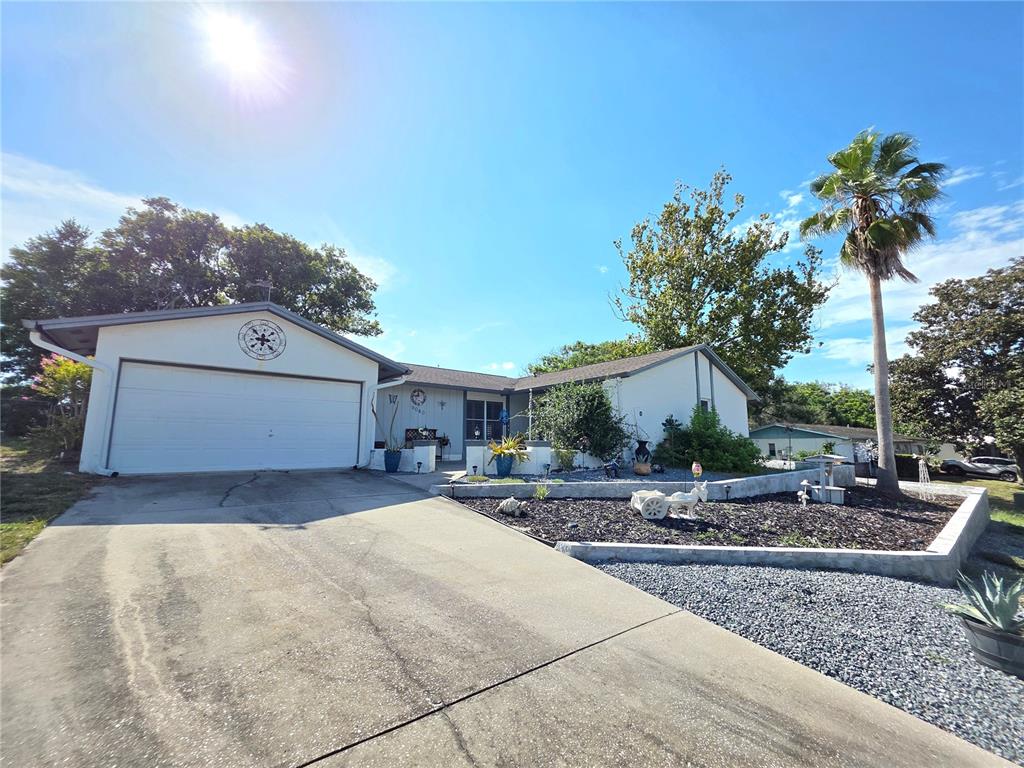 A single-story house with a white exterior, a two-car garage, and a landscaped front yard — 9040 BAY DRIVE, SPRING HILL, FL