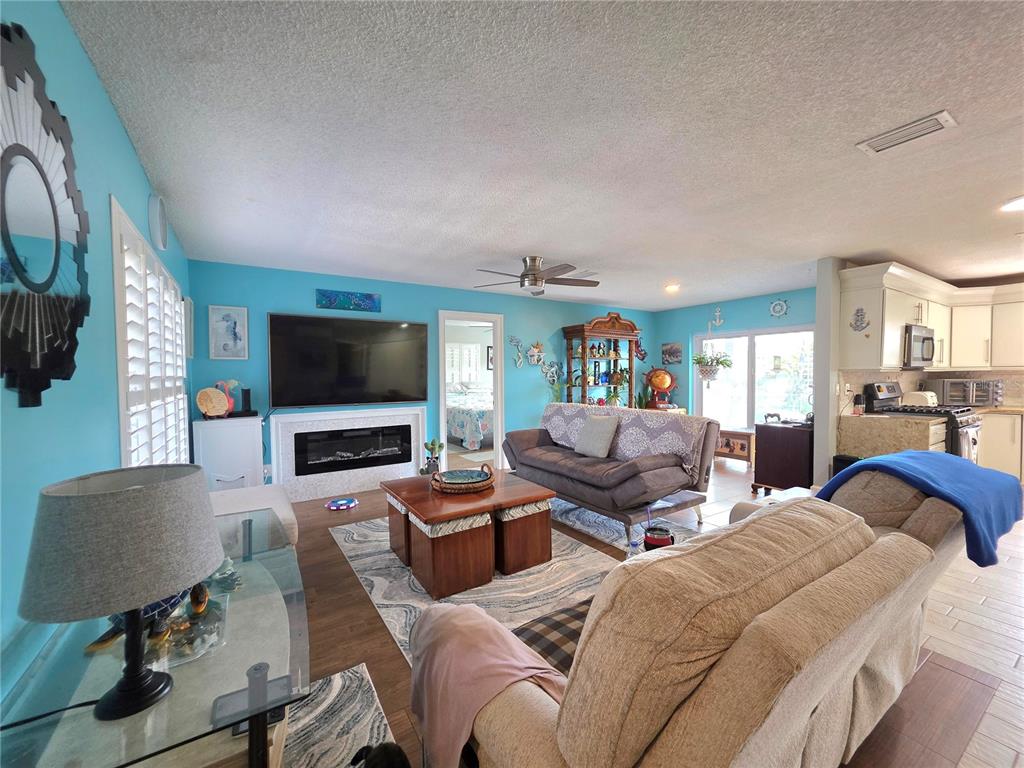 A living room with bright blue walls, a fireplace, and an open-concept kitchen — 9040 BAY DRIVE, SPRING HILL, FL