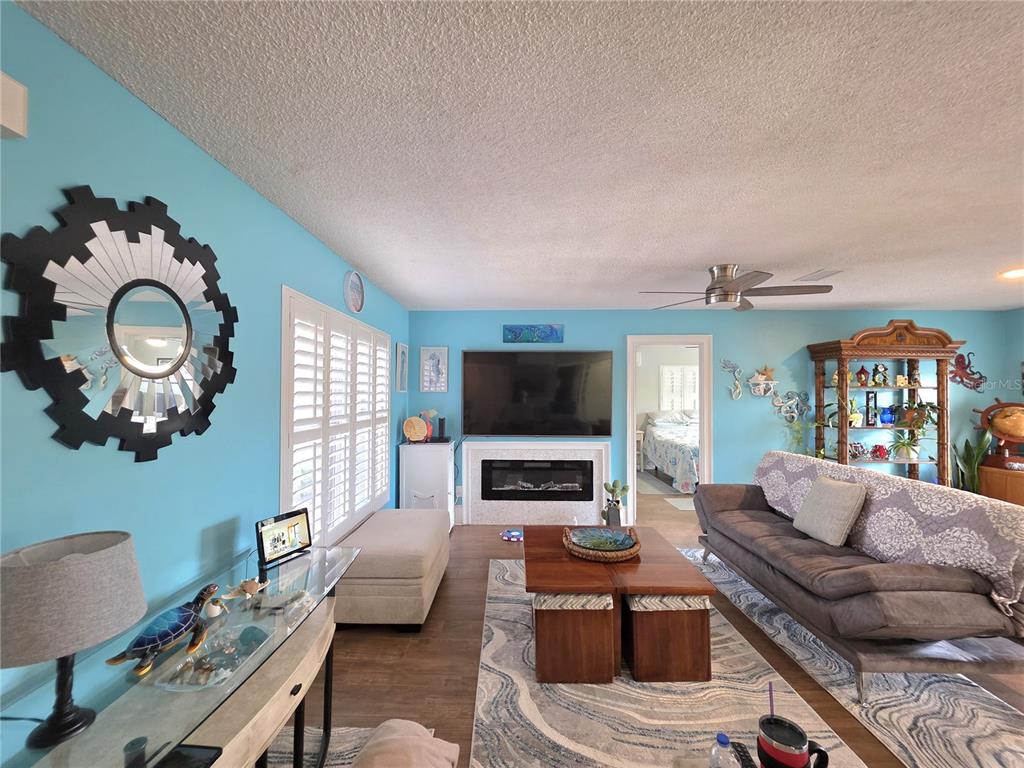 A living room features light blue walls, a fireplace, a sofa, and a glass-topped console table — 9040 BAY DRIVE, SPRING HILL, FL