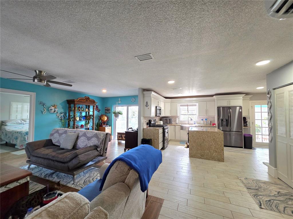An open-concept living room and kitchen featuring light tile floors and a blue accent wall — 9040 BAY DRIVE, SPRING HILL, FL