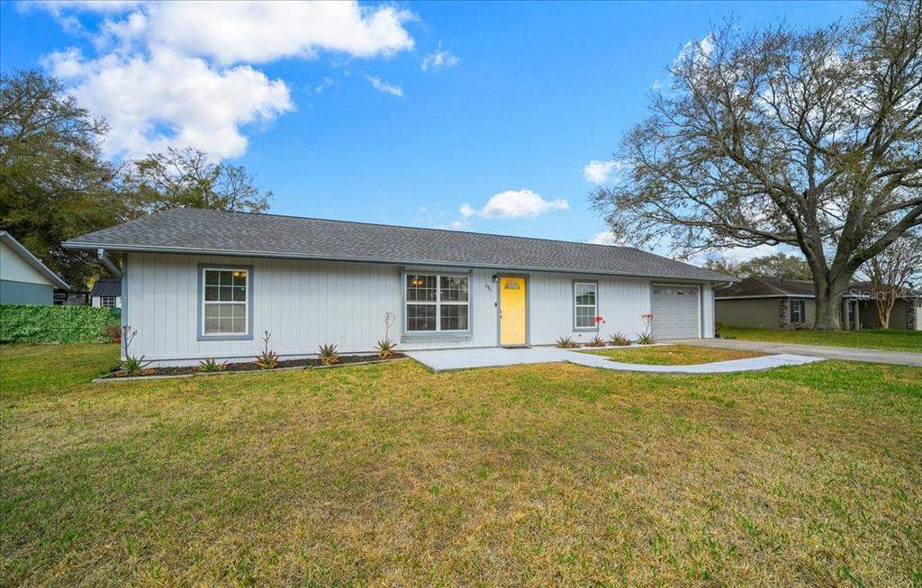 A single-story house with light gray siding, a yellow front door, and a gray roof — 685 NW 67TH PLACE, OCALA, FL