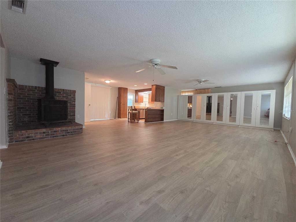 A spacious living room features light wood flooring, a brick fireplace, and mirrored wall panels — 4136 S LOCKWOOD RIDGE ROAD, SARASOTA, FL