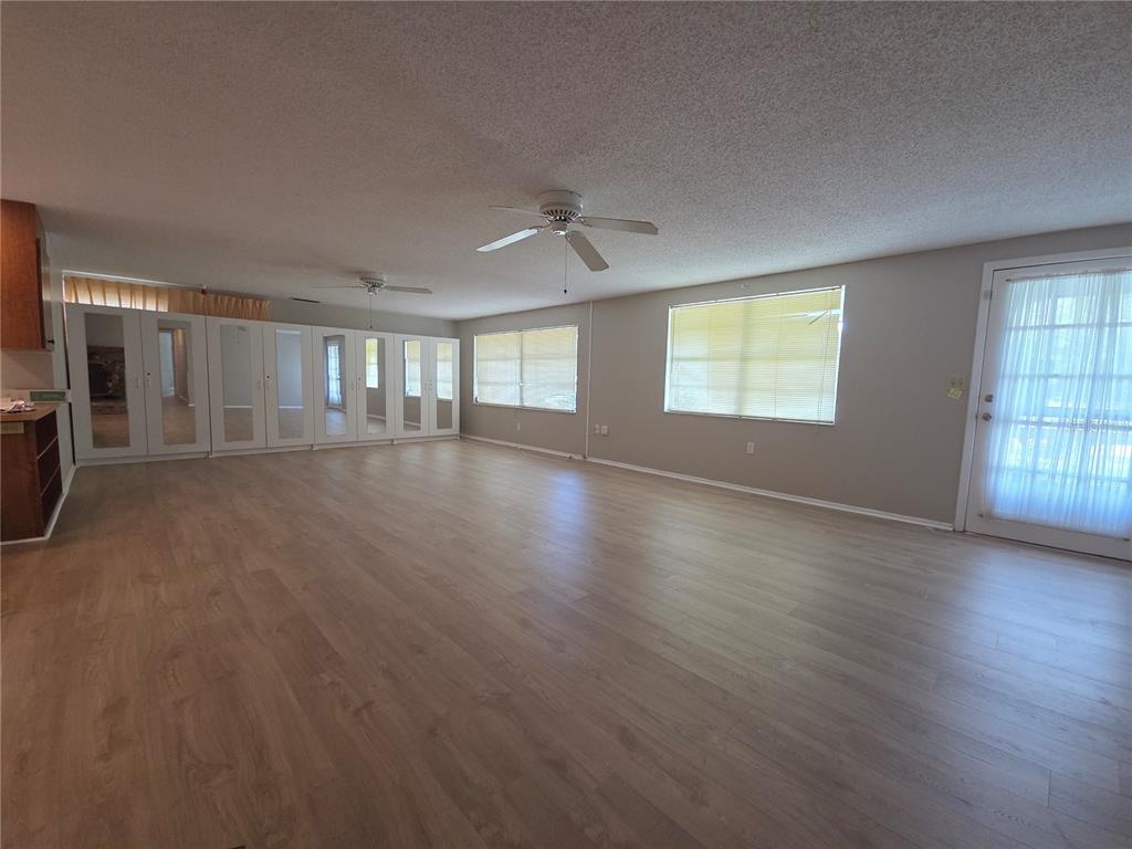 A spacious room features light wood-look flooring, mirrored wall cabinets, two ceiling fans, and windows — 4136 S LOCKWOOD RIDGE ROAD, SARASOTA, FL