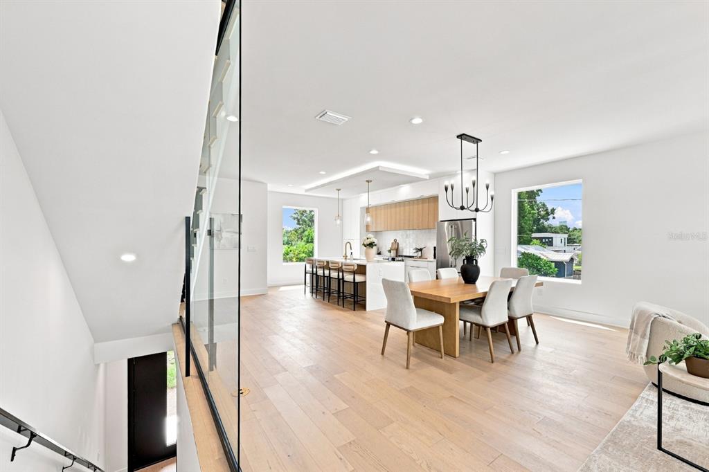 An open-concept kitchen and dining area features light wood floors, white cabinetry, and large windows — 310 W COLUMBUS DRIVE UNIT 4, TAMPA, FL