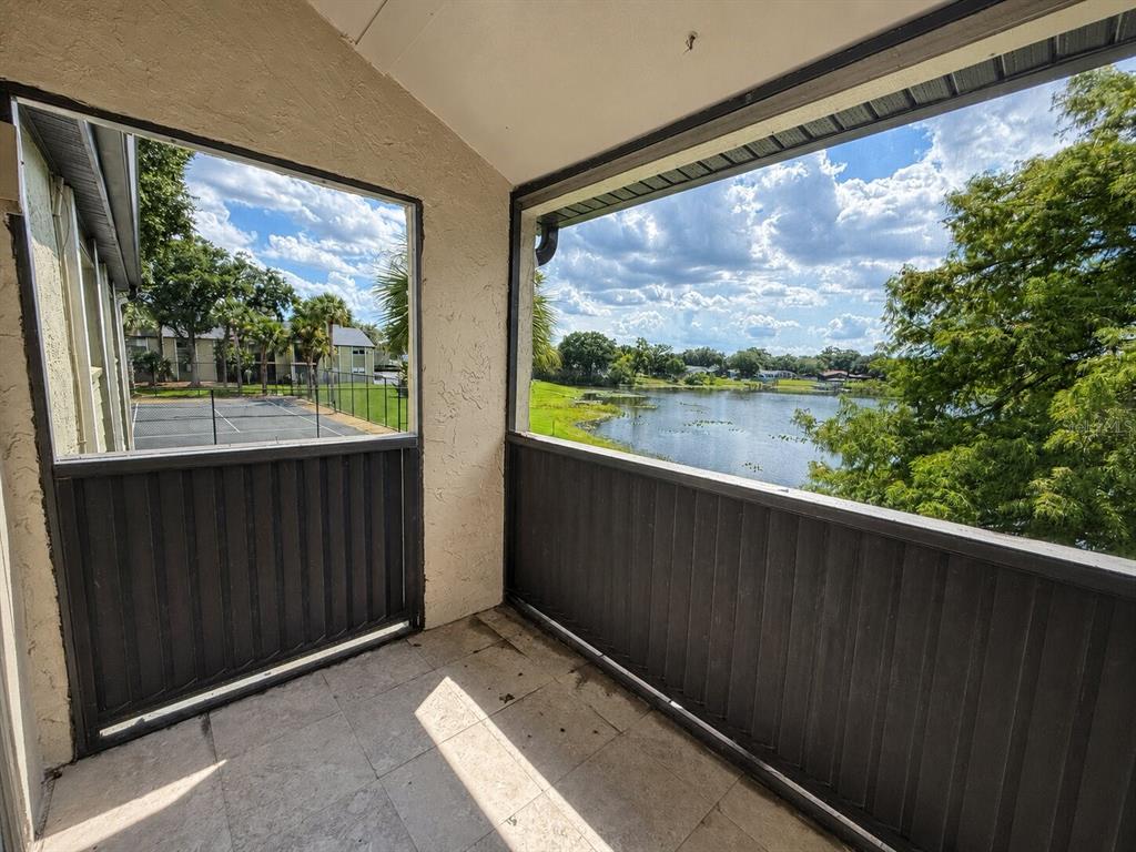 A screened-in balcony with tile flooring overlooks a tennis court and a lake — 914 LAKE DESTINY ROAD UNIT F, ALTAMONTE SPRINGS, FL