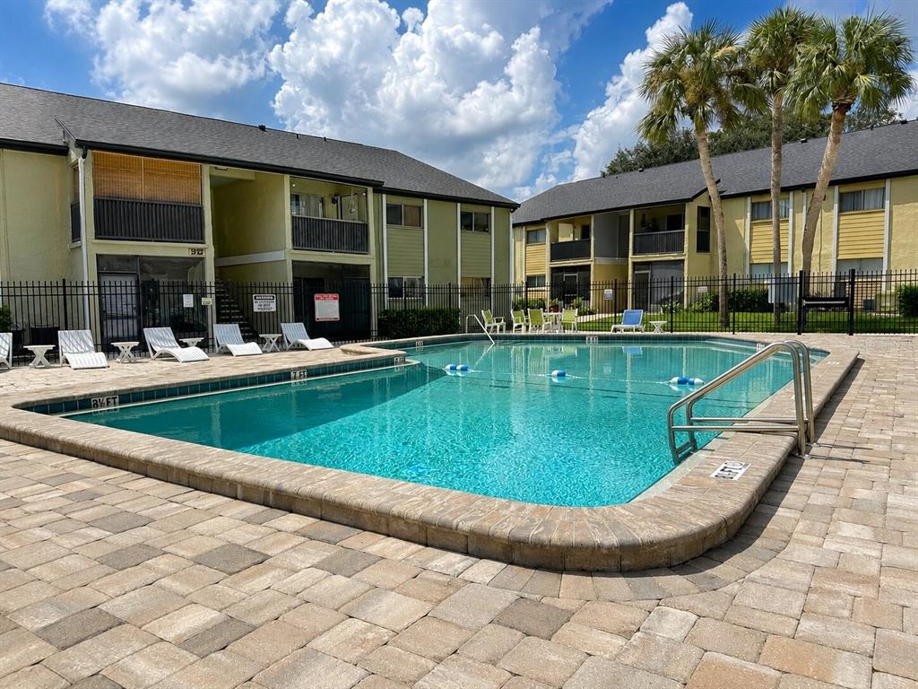 An outdoor swimming pool with a paved deck sits in front of two apartment buildings — 914 LAKE DESTINY ROAD UNIT F, ALTAMONTE SPRINGS, FL