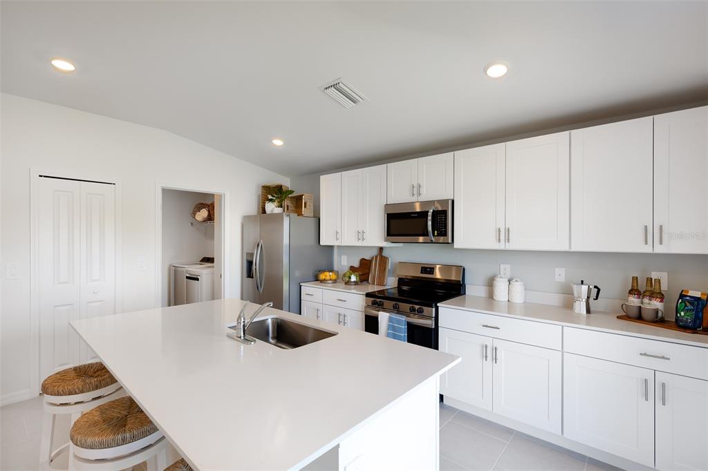 A modern kitchen features white cabinets, stainless steel appliances, and a large central island — 12077 BEIMAN AVENUE, PORT CHARLOTTE, FL