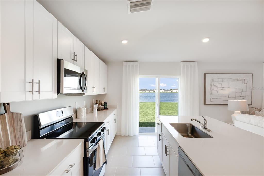 A modern kitchen with white cabinets, stainless steel appliances, and a view of a lake — 12077 BEIMAN AVENUE, PORT CHARLOTTE, FL