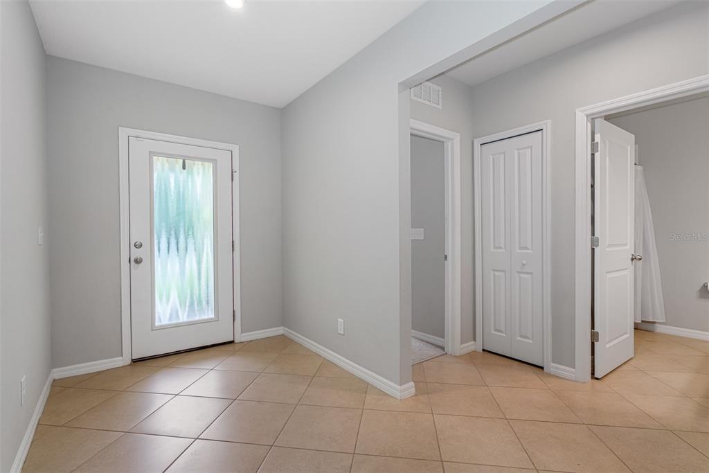 An entryway with light gray walls, tan tile flooring, a front door, and interior doors — 11234 HIGH NOON TRAIL, PARRISH, FL