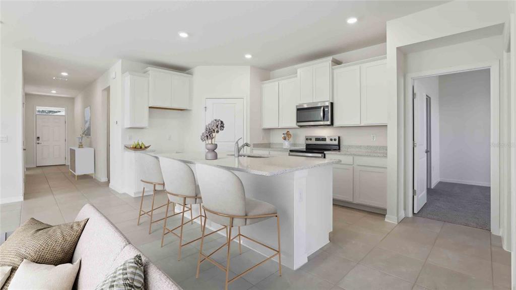 A modern kitchen features white cabinetry, granite countertops, a center island, and three bar stools — 3036 CANOPY OAK BOULEVARD, WILDWOOD, FL