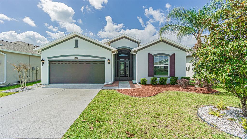 A single-story house features a two-car garage, a front entryway, and a manicured lawn — 9936 GAP WEDGE DRIVE, SAN ANTONIO, FL