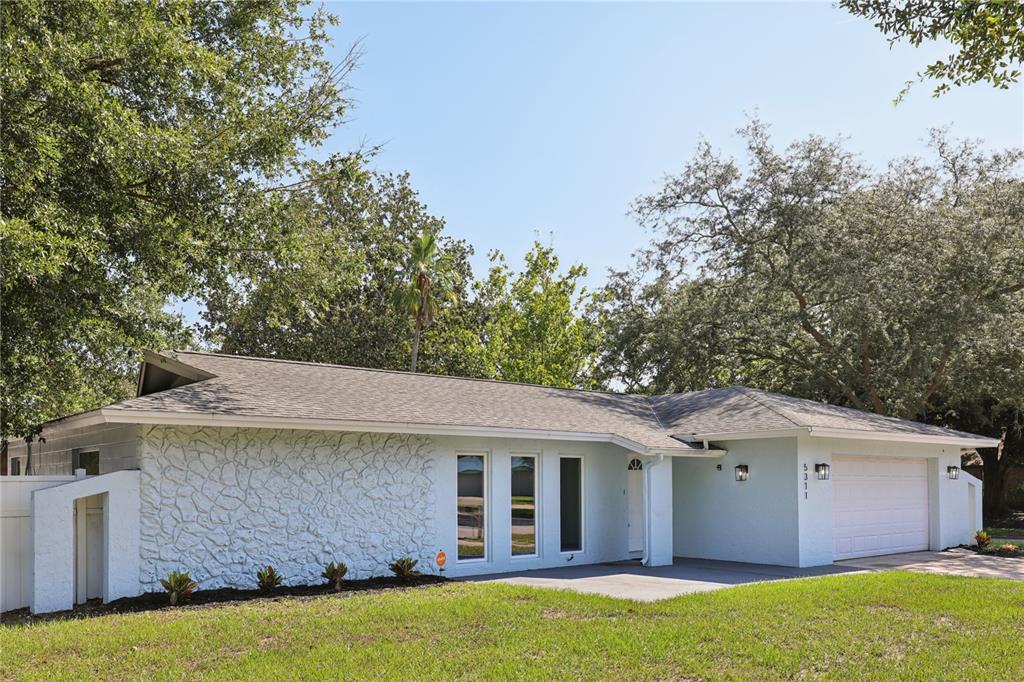 The exterior of a house features a light blue stucco wall, three tall windows, and a white front door — 5311 JENNIFER PLACE, ORLANDO, FL